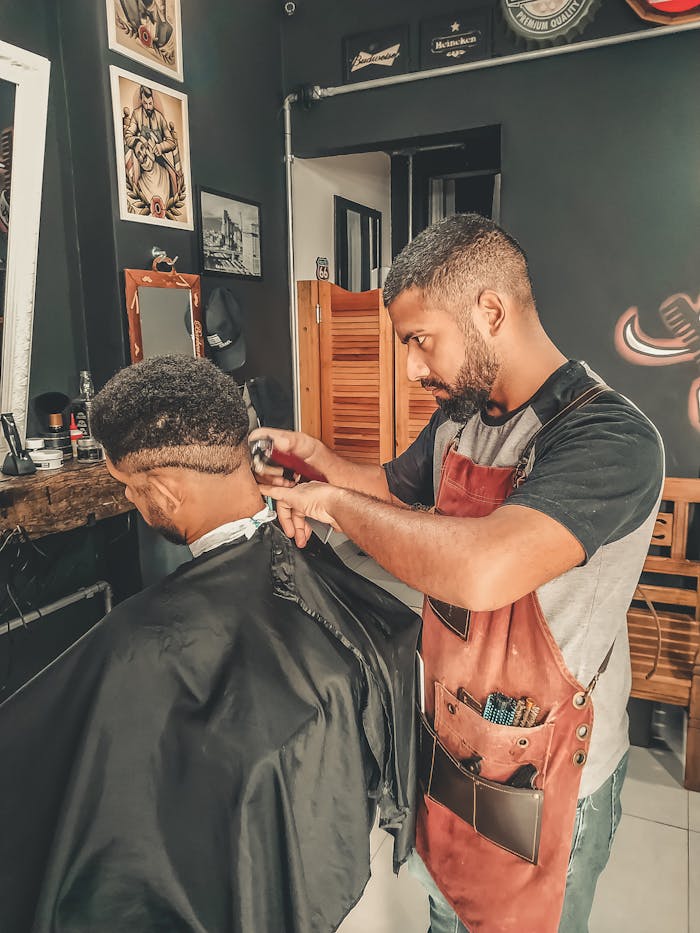 Services Experienced barber styling hair in a modern barbershop setting.
